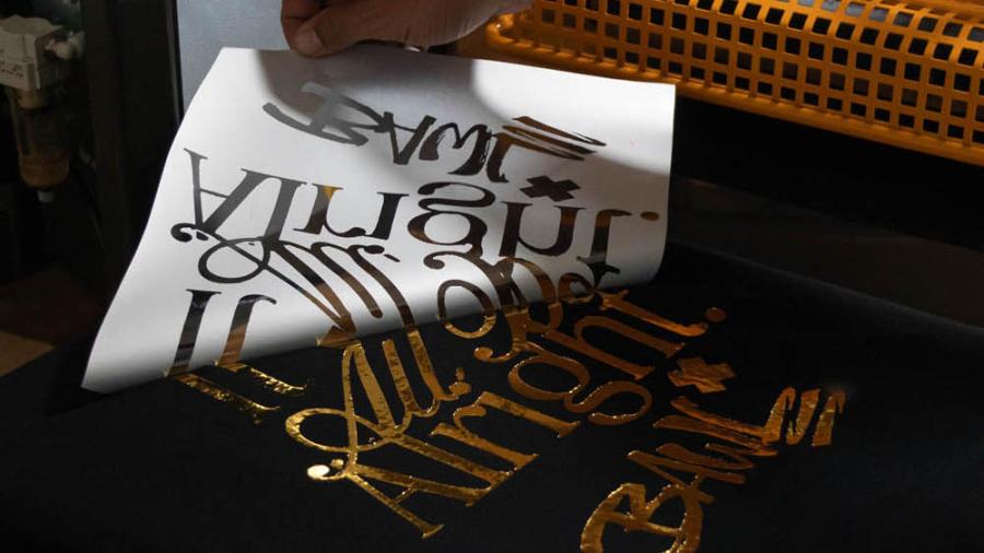 Spellicolamento del transfer DTF Metallic gold foil dopo la pressatura su maglietta nera