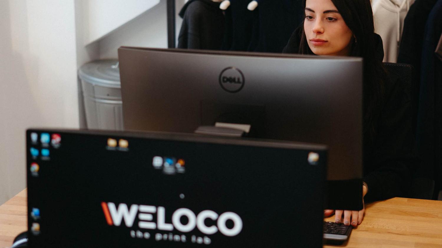 Operatrice Weloco al computer che controlla il file di stampa prima dell'ordine